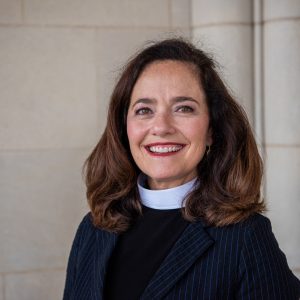 Headshot of Cathedral Vicar, smiling and wearing a pinstriped jacket over priestly vestment