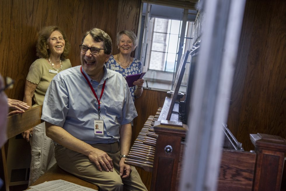 Musician and tour guide with Carillon and visitors in the background, talking and smiling