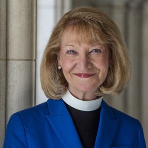 Headshot of Cathedral Provost, smiling and wearing a blue jacket over priestly vestment