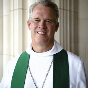 Headshot of Cathedral Dean Randy Hollerith, smiling and wearing priestly vestments