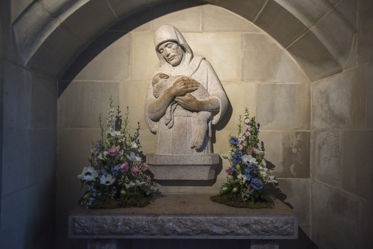 Reredos carving framed by flower arrangements in Cathedral's Good Shepherd chapel