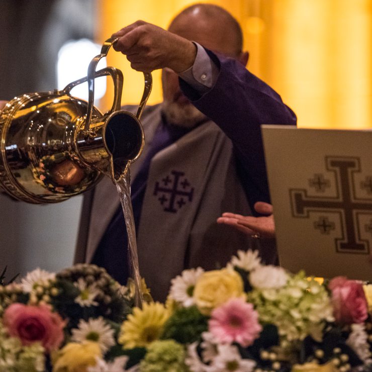 Verger pouring water in preparation for Baptism at Easter