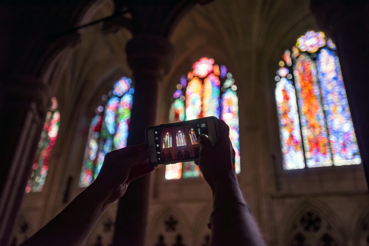 Close-up of visitor taking photo of stained glass windows during sightseeing tour